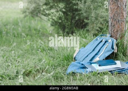 Sac à dos pour l'école, ordinateur portable, ordinateur portable posé dans le parc près de l'arbre, espace de copie Banque D'Images