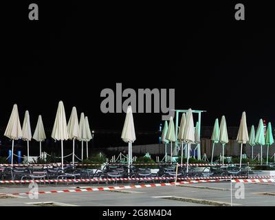 Plage de nuit vide avec chaises longues et parasols pliés clôturée avec ruban barrière Banque D'Images