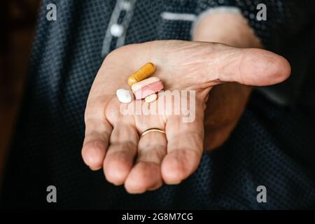 Femme âgée main tenant cinq pilules ou médicaments différents Banque D'Images