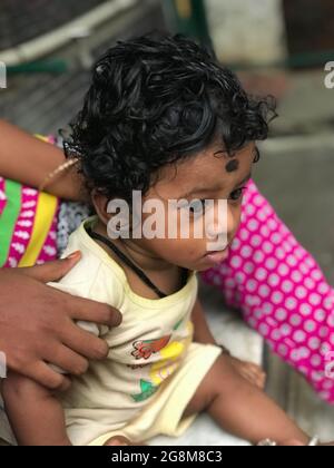 Jeune garçon indien avec des cheveux de curling noirs avec sa sitter de bébé Banque D'Images