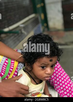 Jeune garçon indien avec des cheveux de curling noirs avec sa sitter de bébé Banque D'Images