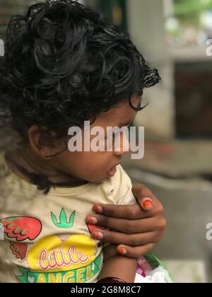 Jeune garçon indien avec des cheveux de curling noirs avec sa sitter de bébé Banque D'Images