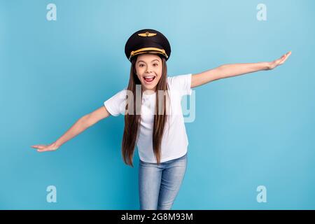 Portrait d'attrayante gai drôle fille port chapeau ayant l'amusement volant comme avion isolé sur fond bleu clair de couleur Banque D'Images