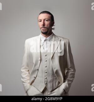 Portrait d'un boss mafieux italien adulte portant un costume blanc sur fond gris Banque D'Images