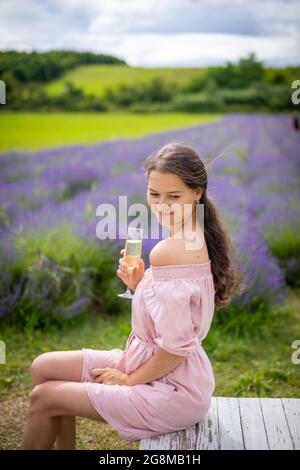 Belle jeune femme se reposant sur un champ de lavande avec un verre de champagne, république tchèque Banque D'Images