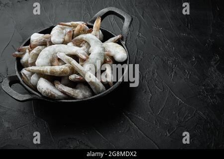 Crevettes tigrées crues non cuites congelées, set de crevettes, dans une poêle en fonte, sur fond de pierre noire, avec espace de copie pour le texte Banque D'Images