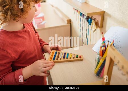 vue rognée d'un enfant jouant à des perles multicolores jeu près de crayons de couleur flous Banque D'Images
