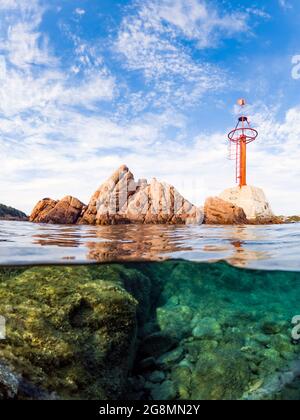 Plan divisé, sur-sous-plan. Vue imprenable sur la moitié du ciel sous-marin avec des rochers et une marque de navigation rouge. Liscia Ruja, Costa Smeralda, Sardaigne. Banque D'Images