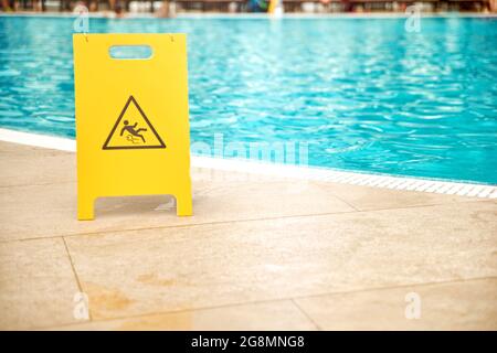 Plaque de sol humide au bord de la piscine en plastique jaune. Banque D'Images