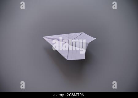 Avion en papier blanc sur fond gris Banque D'Images