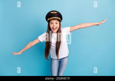 Portrait d'attrayante gai drôle fille port chapeau ayant l'amusement volant comme avion isolé sur fond bleu clair de couleur Banque D'Images