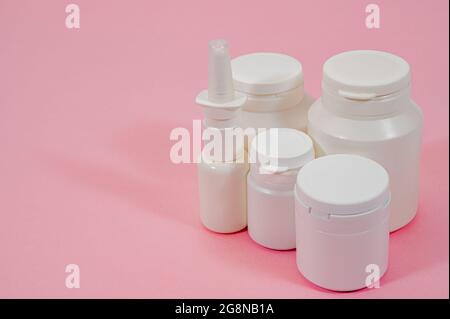 Plusieurs types de flacons de médicaments blancs sur fond rose. Banque D'Images