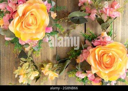 Arrière-plan avec fleurs artificielles sur une table en bois. Roses jaunes et fleurs roses. Mise au point douce Banque D'Images