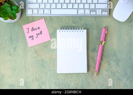 Vue de dessus du bureau avec note avec des mots J'AIME MON TRAVAIL, bloc-notes vide, stylo, clavier, cactus et mause sur une table en bois. Affaires et finance con Banque D'Images