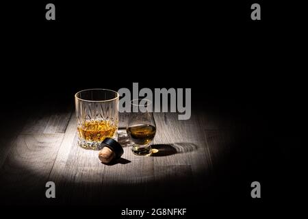 Verres de whisky scotch avec un liège sur une surface en bois sur fond noir avec espace de copie pour le texte Banque D'Images