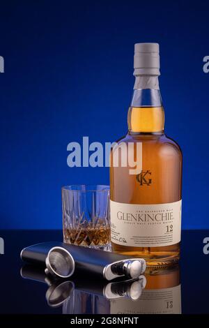 LISSE, PAYS-BAS - 15 JUILLET 2021 : bouteille de Glenkinche et un verre de whisky scotch de 12 ans sur une surface réfléchissante sur fond bleu. Banque D'Images