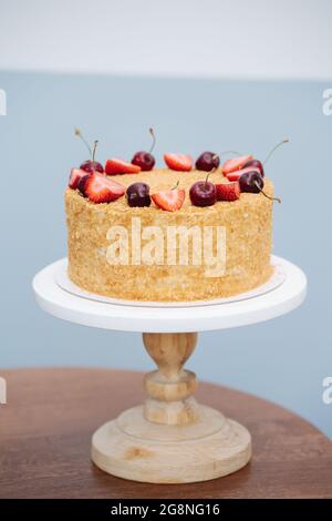 Gâteau au miel russe sur une assiette surélevée décorée de baies. Sur une table ronde sur un mur blanc et bleu. Banque D'Images