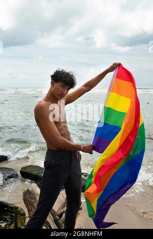 Portrait d'un jeune gay hispanique regardant la caméra, portant le drapeau LGBT - Focus sur l'image verticale du visage Banque D'Images