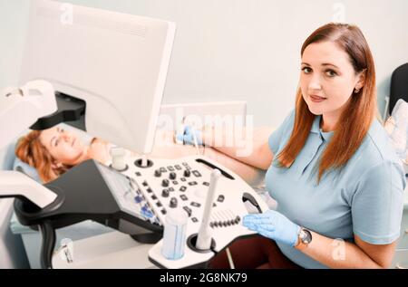 Échographiste en gants stériles examinant une patiente avec un échographe. Femme médecin effectuant un examen échographique. Concept de soins de santé, ultr Banque D'Images