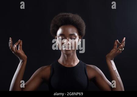 Portrait en studio du modèle féminin afro-américain montrant le mudra zen yoga ou le geste du signe OK. Femme paix intérieure, santé et méditation Banque D'Images