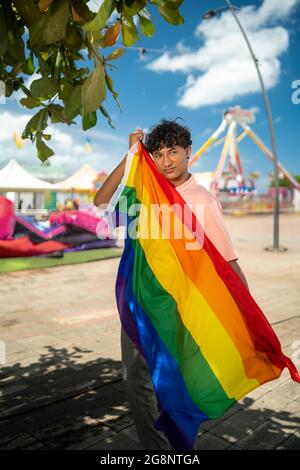 Portrait d'un jeune gay hispanique regardant la caméra, portant le drapeau LGBT - Focus sur l'image verticale du visage Banque D'Images