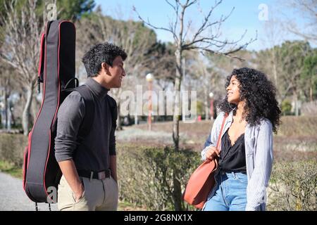 Amis latins parlant au campus de l'université avec un cas de guitare. Vie universitaire. Banque D'Images