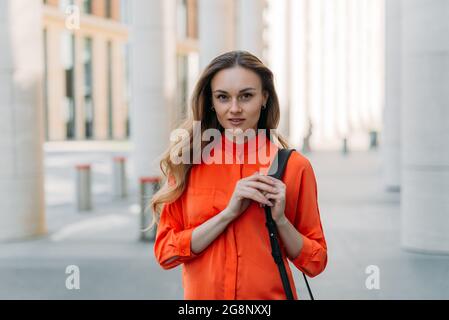 Belle fille caucasienne avec des cheveux amples dans la ville regarde la caméra Banque D'Images