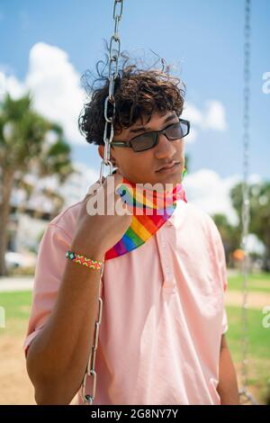 Portrait d'un jeune gay hispanique regardant la caméra, portant le drapeau LGBT - Focus sur l'image verticale du visage Banque D'Images