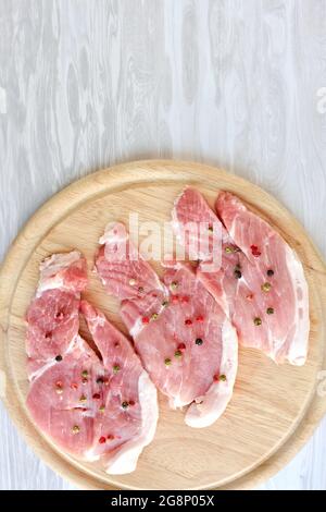 morceaux de viande de porc hachés assaisonnés de différents poivrons et disposés sur une planche à découper en bois Banque D'Images