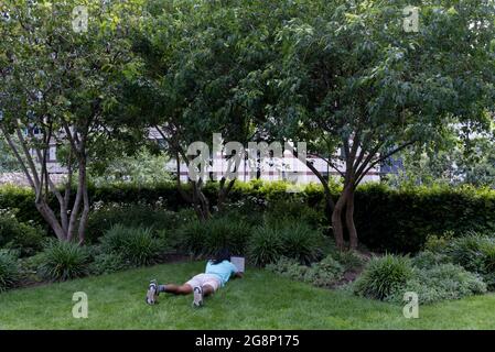 Un jour après la « Journée de la liberté » de Covid, où la distanciation sociale et le port de couvre-visage ne sont plus obligatoires, un homme se trouve sur l'herbe sous des locaux de bureau largement vides, car la majorité des employés de la ville travaillent encore à domicile, le 21 juillet 2021, à Londres, en Angleterre. Banque D'Images