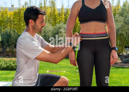 Un entraîneur de forme physique mesure la taille d'un client sur un programme de perte de poids, un régime et une formation. Résoudre le problème de l'obésité. Banque D'Images