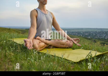 Homme amateur de yoga relaxant et atteignant la paix intérieure pratiquant la méditation dans la nature Banque D'Images