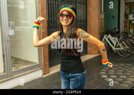 Cool italienne femme avec LGBT poignet et bandeau montrant son muscle sur un fond flou Banque D'Images