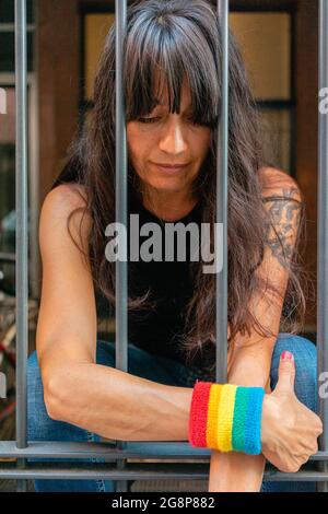 Petit foyer d'une femme italienne avec un bracelet LGBT derrière les barreaux Banque D'Images