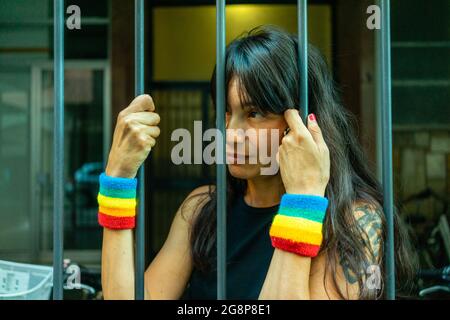 Petit foyer d'une femme italienne avec des bracelets LGBT derrière les barreaux Banque D'Images