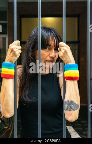 Petit foyer d'une femme italienne avec des bracelets LGBT derrière les barreaux Banque D'Images