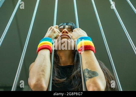 Petit foyer d'une femme italienne avec des bracelets LGBT derrière les barreaux Banque D'Images