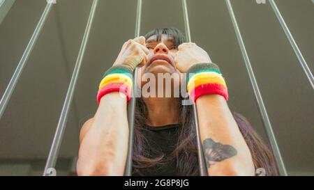 Petit foyer d'une femme italienne avec des bracelets LGBT derrière les barreaux Banque D'Images