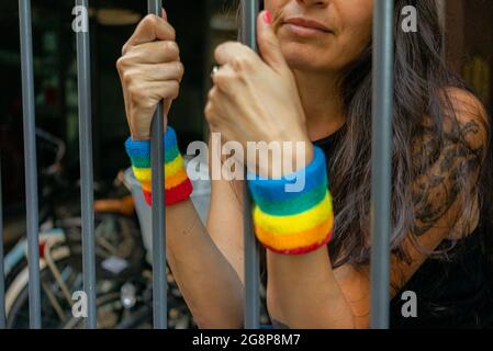 Petit foyer d'une femme italienne avec des bracelets LGBT derrière les barreaux Banque D'Images