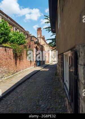 En regardant le long de la rue pavée Chapter House avec la maison des trésors sur la gauche York Yorkshire Angleterre Banque D'Images