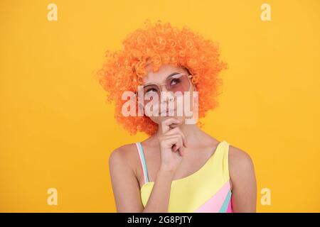 enfant en train de penser dans la perruque de clown. s'amuser. enfant réfléchit porter des lunettes de soleil et un maillot de bain. Banque D'Images