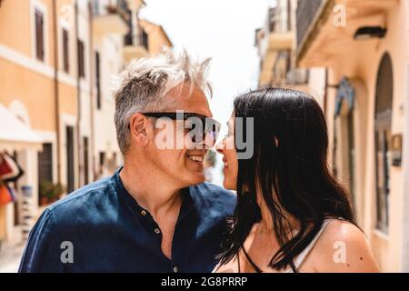 Beau couple avec une femme mignonne et un homme tendance d'âge moyen regardant dans les yeux de l'autre et posant pour une photo pendant les vacances d'été dans une image Banque D'Images