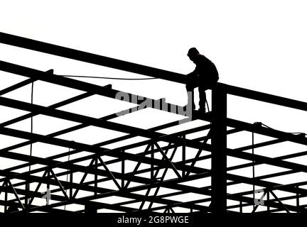 Un homme assis sur une poutre en treillis d'acier, des tuyaux chromés isolés sur le fond. Art design structure de construction métallique horizontale pour entrepôt de toit. Abstr Banque D'Images