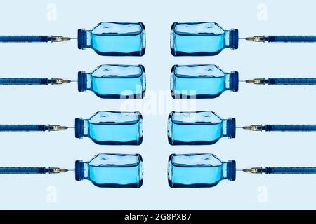 certains flacons de vaccins contenant un liquide bleu et certaines seringues collées sur eux, disposés en différentes lignes sur un fond bleu pâle Banque D'Images