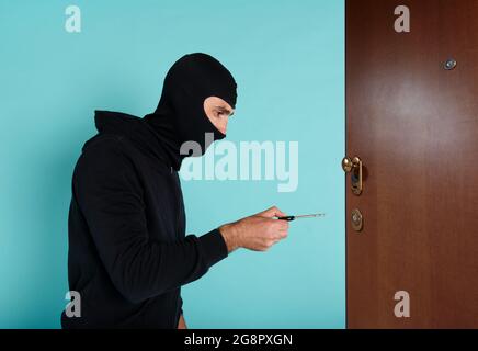 Voleur avec balaclava tente d'ouvrir la porte de l'appartement avec une clé Banque D'Images