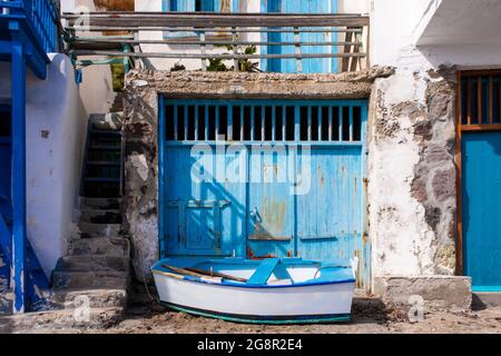 Portes de garage bleu vif avec un petit bateau en bois devant dans le village grec des pêcheurs de Klima - le village le plus coloré de Grèce. Banque D'Images