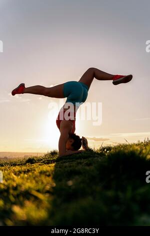 Femme non reconnue portant des vêtements de sport faisant de la pose de yoga et de l'entraînement dans le parc. Elle est forte et flexible. Banque D'Images