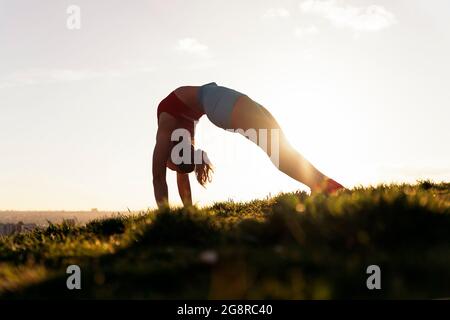 Jeune femme chinoise portant des vêtements de sport s'étirant après son entraînement dans le parc. Elle est forte et flexible. Banque D'Images