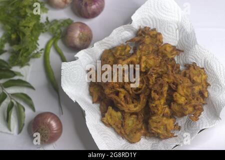 Beignets d'oignons. Tranches d'oignons frits enrobées de farine hachée et de masala. Une collation populaire en Inde communément connue sous le nom de pakoda d'oignon. Prise de vue sur b blanc Banque D'Images