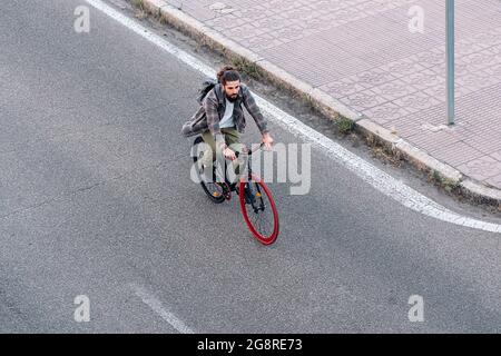 Beau boxeur avec de longs cheveux regardant devant et de conduire son vélo sur la route. Banque D'Images